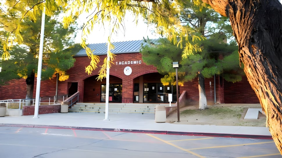 El edificio con techo rojo y letrero de Academic en el Mesa Unified School District está rodeado de árboles y tiene un camino pavimentado hacia la entrada.
