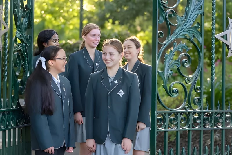 Un grupo de estudiantes está frente a una puerta de metal decorada en el campus del Methodist Ladies' College.