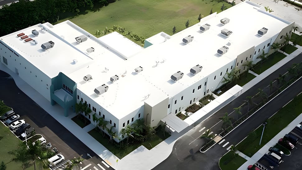 El moderno edificio escolar de la Miami Arts Charter School con área verde circundante y vehículos estacionados.