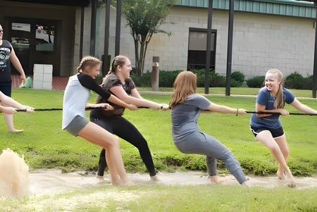 Estudiantes de la Miami Arts Charter School están en un campo frente a un edificio haciendo ejercicios físicos juntos.