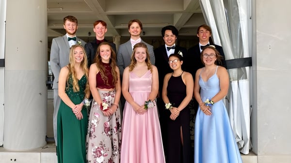 Un grupo de estudiantes de la Michigan Lutheran High School en un evento formal frente a un fondo arquitectónico.