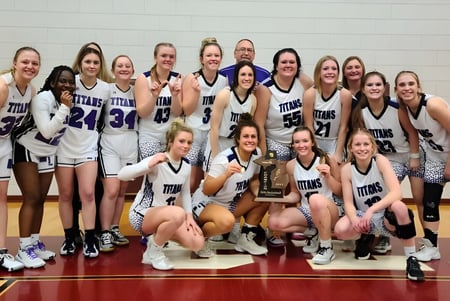Estudiantes de la Michigan Lutheran High School celebran en la cancha de baloncesto su victoria con un trofeo.