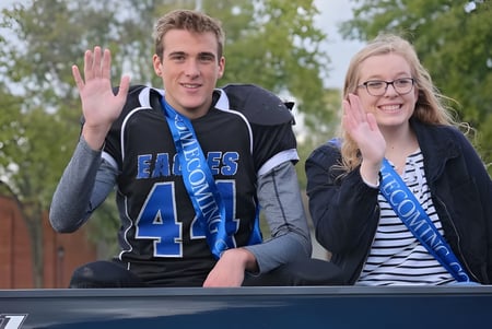 Dos estudiantes de la Middletown Christian School están sentados en un banco al aire libre y saludan a la cámara.