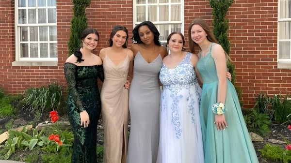 Un grupo de cinco estudiantes de la Middletown Christian School está frente a un edificio de ladrillo con un fondo verde.