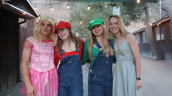 Cuatro alumnas en coloridos disfraces están juntas al aire libre en el campus de la Midland School.