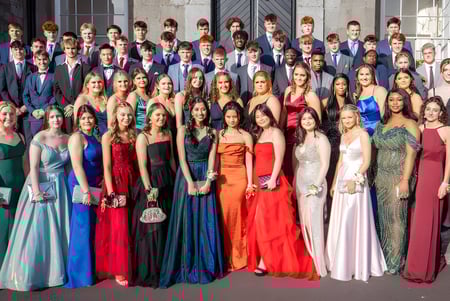 Un grupo de estudiantes del Midleton College está vestido con ropa formal frente a un edificio de piedra.