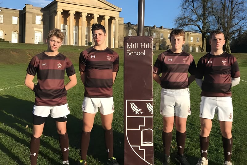 Un grupo de estudiantes en uniformes deportivos está frente al edificio escolar de la Mill Hill School.