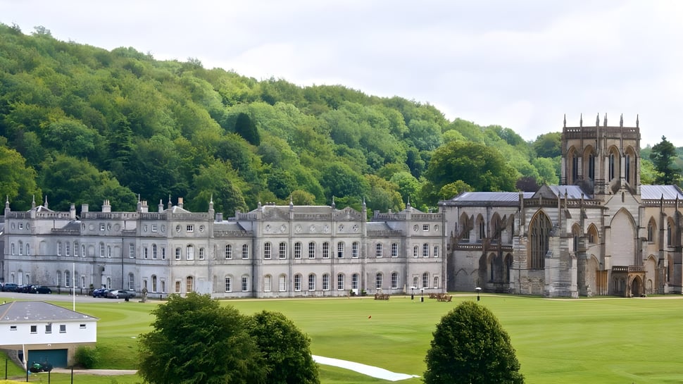 El histórico edificio principal de la Milton Abbey School está rodeado de áreas verdes y árboles.