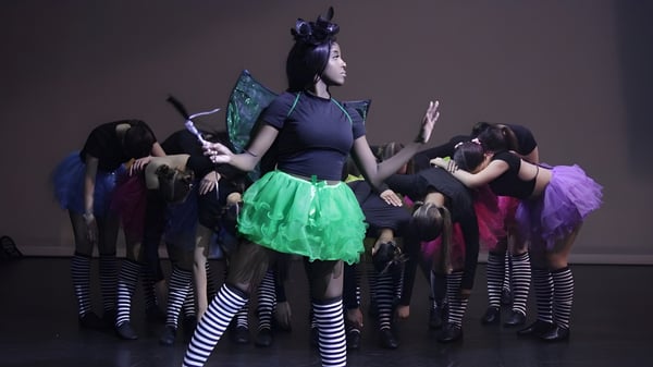 Estudiantes del Mindarie Senior College realizan un baile en un escenario con coloridos trajes.