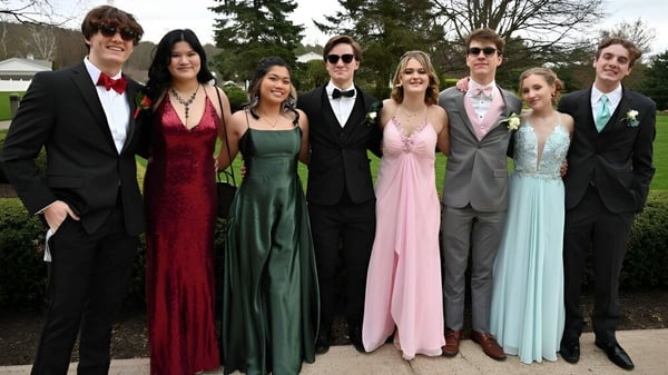 Un grupo de personas está de pie formalmente frente a árboles y un pabellón en el terreno de la Miramichi Valley High School.