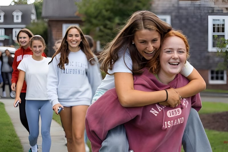 Un grupo de alumnas de Miss Porter's School camina juntas por el campus con edificios y áreas verdes de fondo.