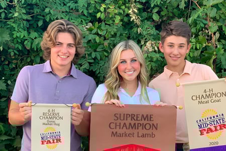 Tres estudiantes de la Mission College Preparatory Catholic High School presentan sus premios ganados frente a un entorno verde.