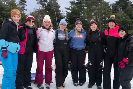 Un grupo de estudiantes de la Mobile Central High está de pie con ropa de invierno en un bosque nevado.