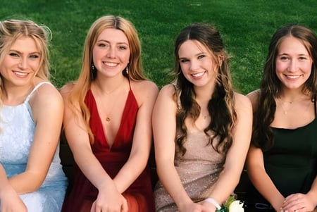 Cuatro estudiantes de la Monarch High School posan juntas en un prado cubierto de hierba.