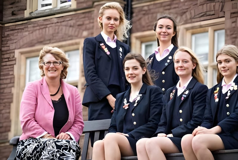 Un grupo de alumnas de la Monmouth School for Girls está juntas frente a un edificio de ladrillo rojo.