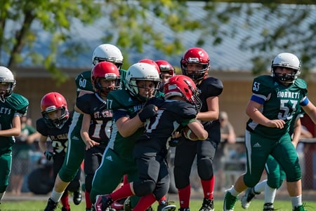 Un grupo de jóvenes futbolistas está en el campo de fútbol de la Montcalm Secondary School con árboles al fondo.