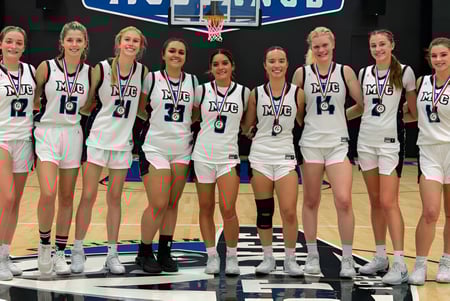 Un grupo de jóvenes jugadoras de baloncesto está en la cancha de baloncesto de la Monte Vista Christian School.