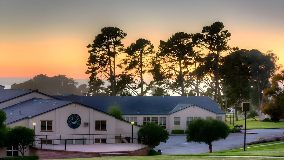 El vecindario con altos pinos frente al colorido atardecer en el campus de la Monterey Bay Academy.