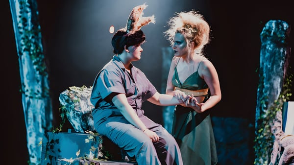 Dos personas se abrazan en el escenario de la Montpelier High School frente a un telón de fondo de exuberante follaje y luces de escenario.