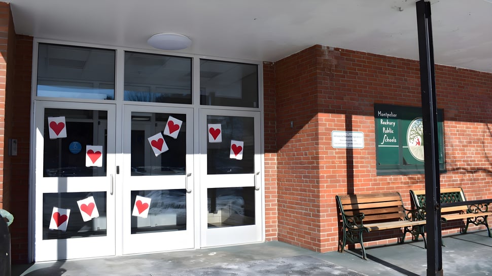 El edificio de ladrillo con ventanas de vidrio y decoraciones en forma de corazón en el terreno de la Montpelier Roxbury Public School District.