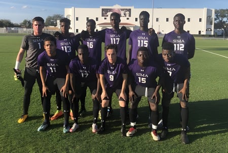 Un grupo de futbolistas en camisetas moradas está en el campo de la Montverde Academy frente a un edificio.