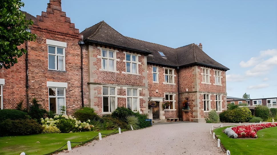 El edificio de ladrillo de la Moreton Hall School está rodeado de un jardín cuidado con flores de colores.