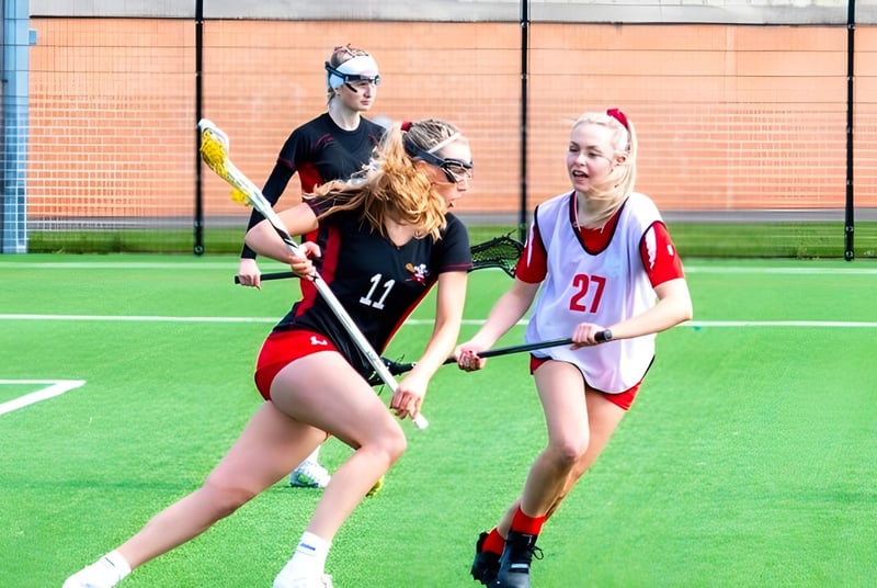 Las alumnas de la Moreton Hall School juegan un partido de hockey en el campo de césped artificial frente a un edificio de ladrillo.