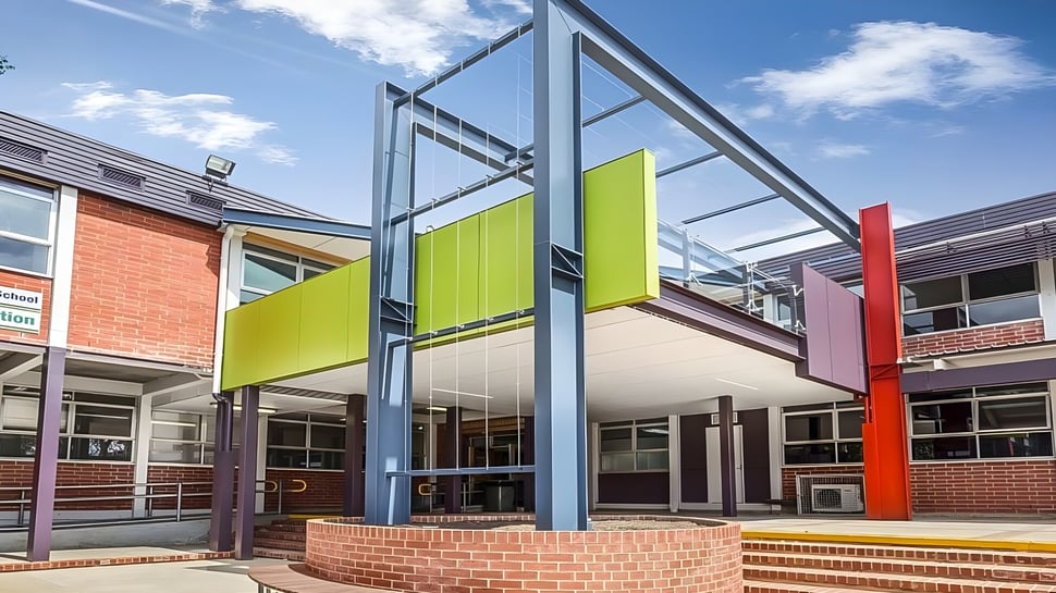 El moderno edificio multicolor de la Mount Barker High School se ve con estructuras de vidrio y acero bajo un cielo azul.