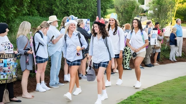 Un grupo de estudiantes de la Mount De Sales Academy camina juntos por un camino rodeado de árboles.