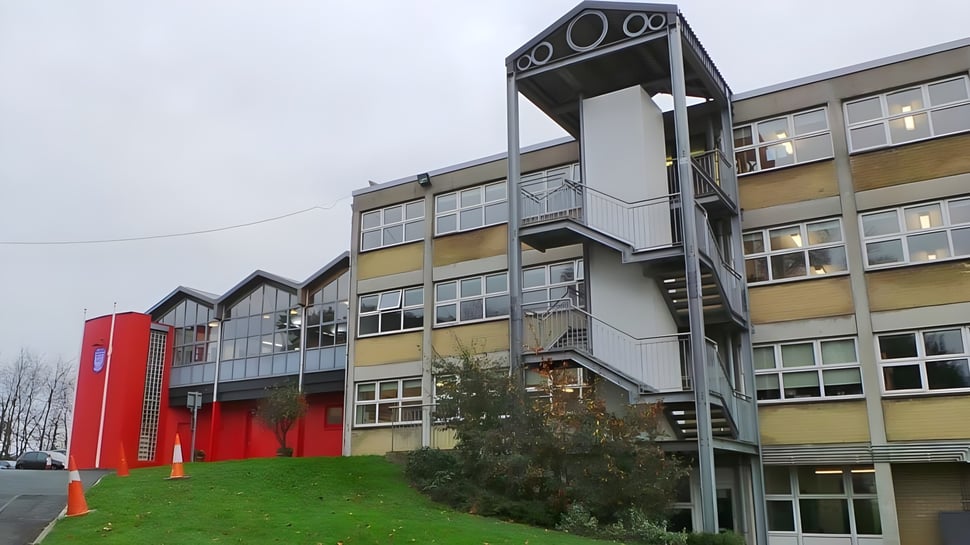 El edificio de varios pisos de la Mount Sackville Secondary School con fachada amarilla y roja está rodeado de un área verde con árboles.