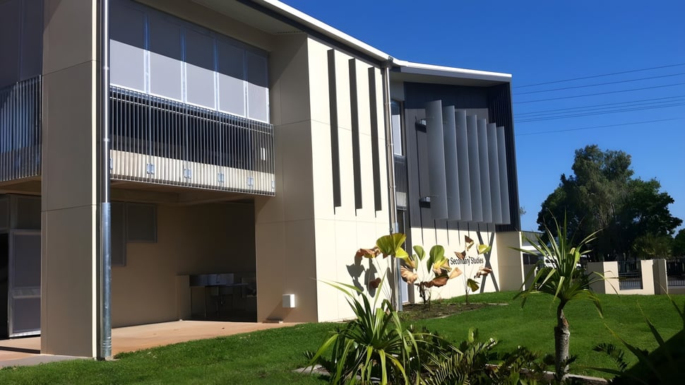 El moderno edificio de varios pisos con elementos de vidrio y concreto pertenece al Moyne College y se encuentra frente a un cielo despejado y áreas verdes.