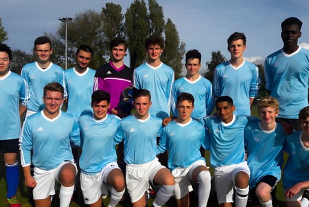 Un grupo de jóvenes futbolistas posan con el uniforme del equipo en un campo en el campus de MPW Cambridge.