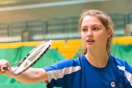Una estudiante de la MPW London juega un partido de tenis en la cancha de tenis verde de la escuela.