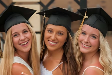 Tres estudiantes de la Mt. Vernon High School posan con ropa de graduación frente a un fondo de madera.