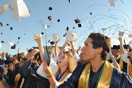 Las graduadas y graduados del Murrieta Valley Unified School District celebran su fiesta de graduación bajo un cielo azul con diplomas y confeti.