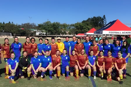 Un grupo de jóvenes futbolistas posa en el campo de fútbol del Murrumba State Secondary College frente a una carpa de la Football Academy.