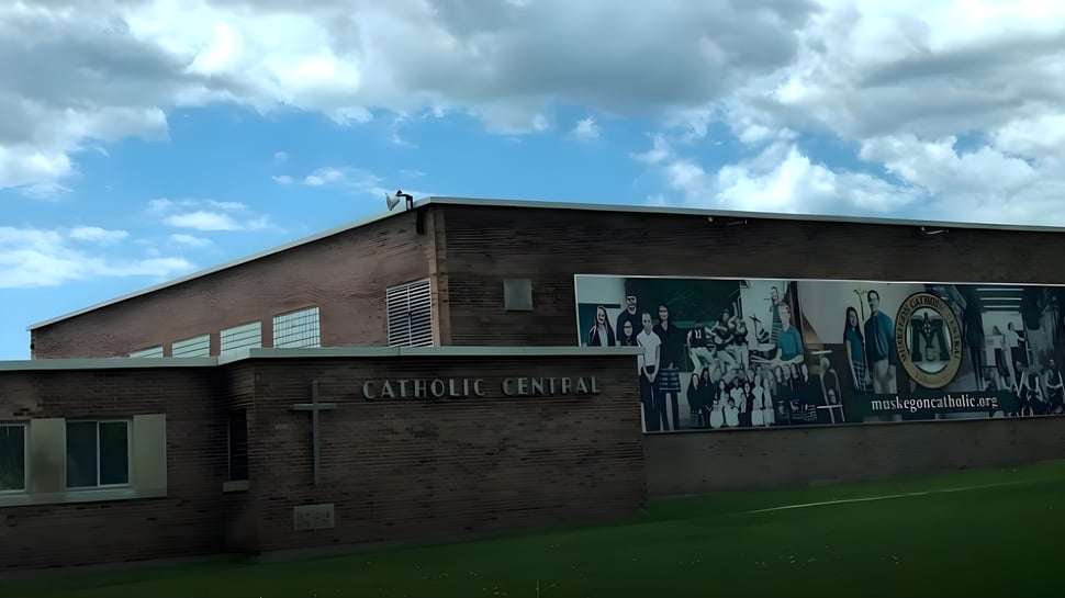 El edificio de ladrillo de la Muskegon Catholic Central High School frente a un cielo azul nublado.