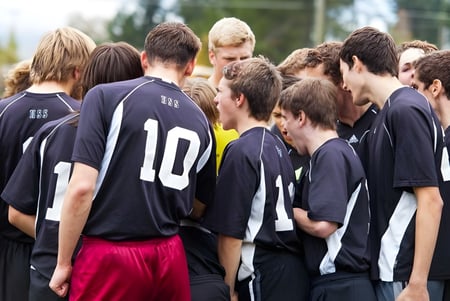 Un grupo de estudiantes de la Nakusp Secondary School está con camisetas negras afuera frente a árboles.