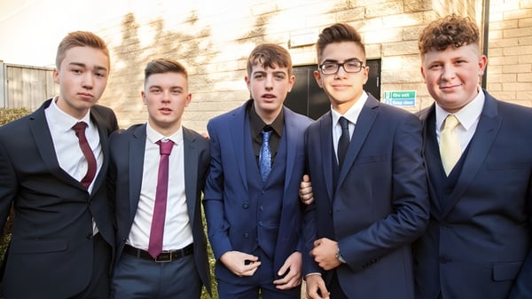 Un grupo de cinco estudiantes en ropa formal está frente a un edificio de ladrillo en el campus de la Napier Boys High School.