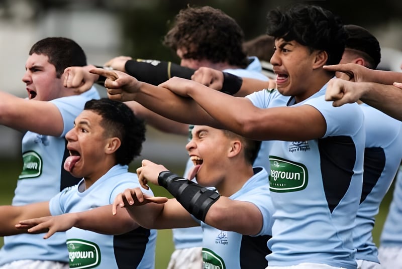 Un grupo de jóvenes atletas en uniformes deportivos juega o celebra al aire libre en el terreno de la Napier Boys High School.