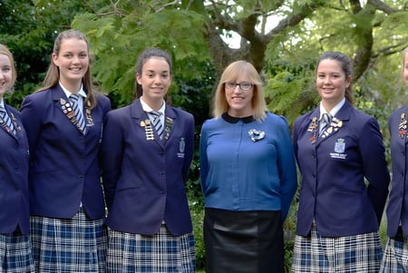 Un grupo de alumnas está juntas en el área verde exterior de la Napier Girls' High School.