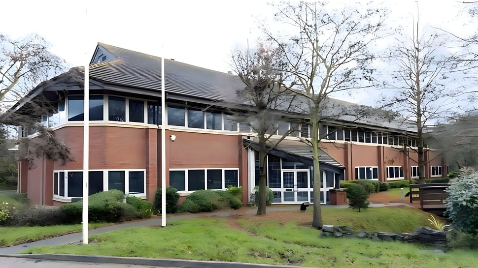 El edificio de ladrillo de varios pisos del National Mathematics and Science College está rodeado de árboles y una zona verde.