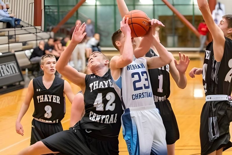 Estudiantes de Nebraska Christian Schools juegan baloncesto en la cancha con espectadores al fondo.