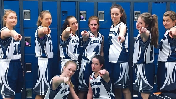 Un grupo de jóvenes atletas de la Nechako Valley Secondary School posan juntas en el vestuario con ropa deportiva.
