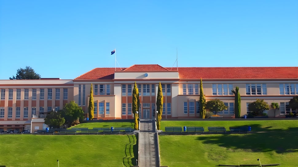 El edificio de varios pisos con techo de tejas rojas se encuentra en el campus del Nelson College for Boys en un día soleado.