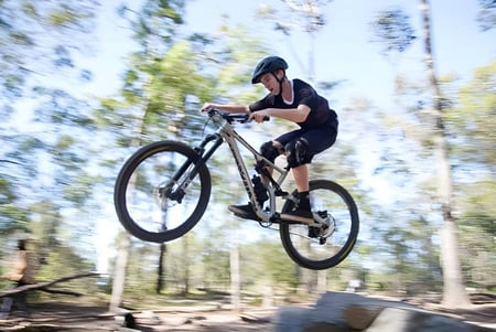Una persona monta en bicicleta a través de un área boscosa en el terreno de la Nerang State High School.