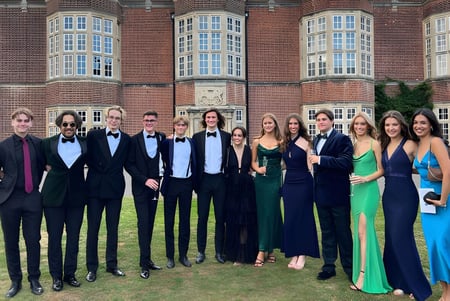 Un grupo de personas posa frente al histórico edificio de ladrillo de la New Hall School.