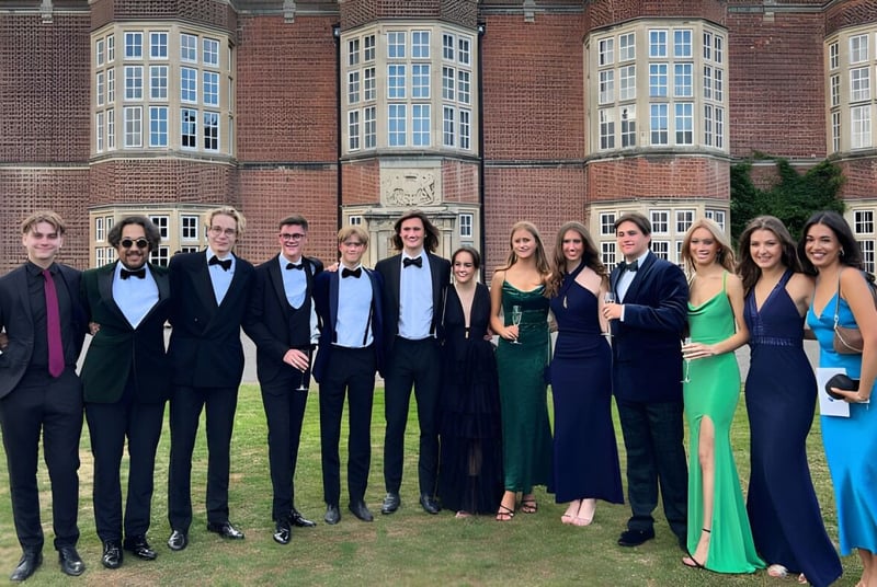 Un grupo de personas posa frente al histórico edificio de ladrillo de la New Hall School.