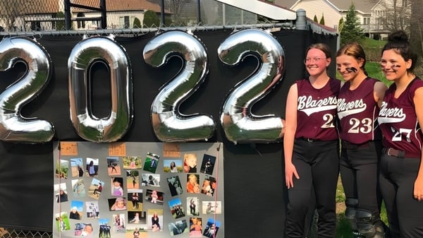 Tres estudiantes están de pie frente a grandes números inflables con el año 2022 en la N.E.W. Lutheran High School.