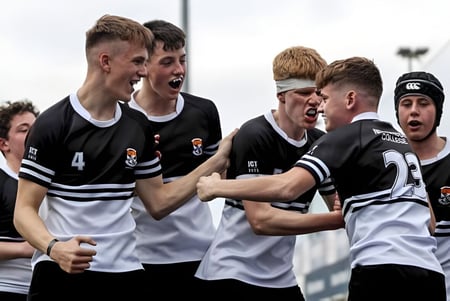 Un grupo de estudiantes en ropa deportiva celebra juntos en el campo del Newbridge College.